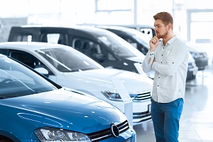 Young adult in car showroom looking at cars